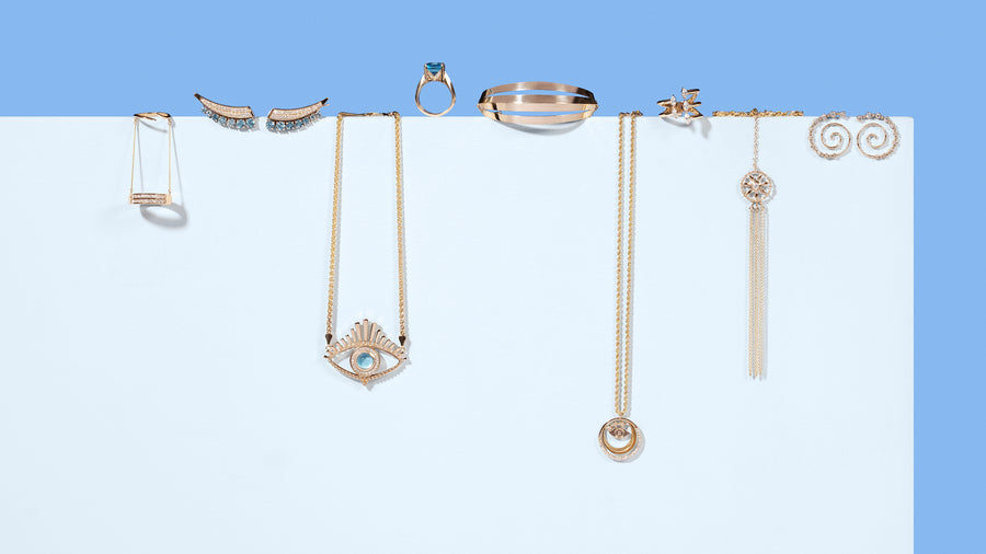 Stylized jewelry photography. Variety of gold rings, earrings, necklaces, and bracelets with gold and blue topaz gemstones