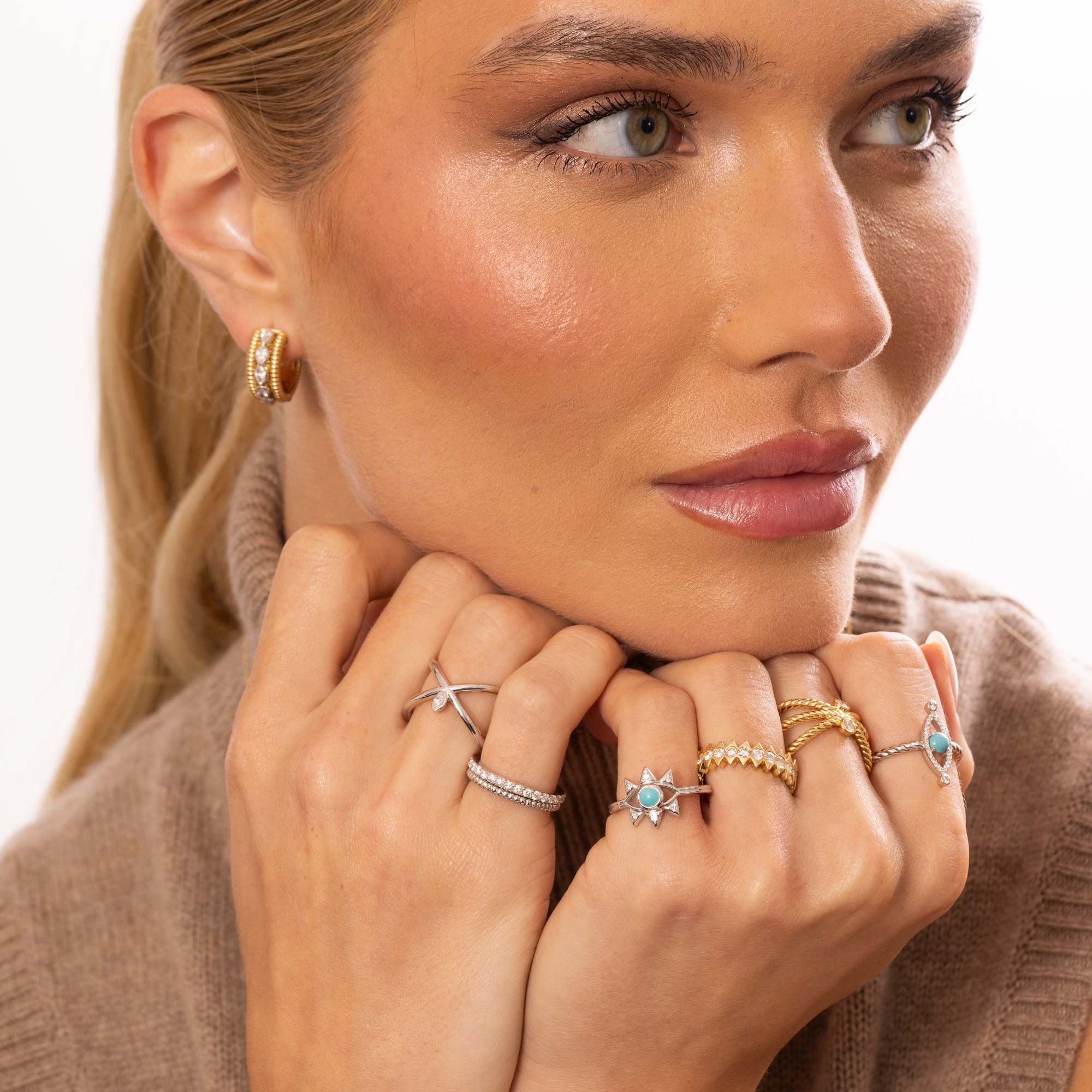 Woman wearing multiple rings on her fingers with a neutral background