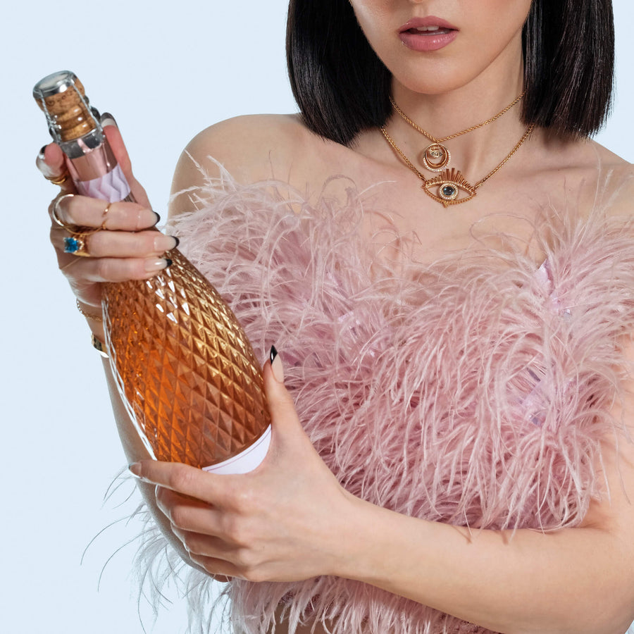 Woman popping champagne wearing lots of gold jewelry