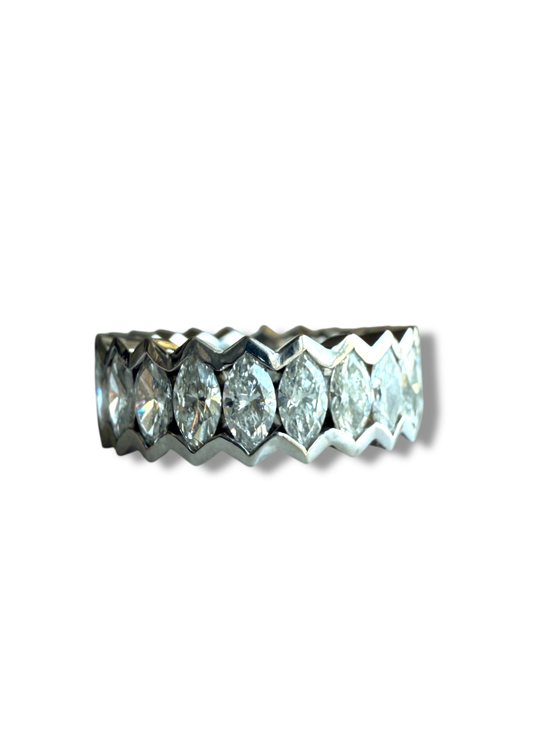 The Nijma M Fine Jewelry Marquise Diamond Eternity Ring in 18K white gold showcases marquise diamonds set in a zigzag pattern, shown on a white background with a subtle shadow.