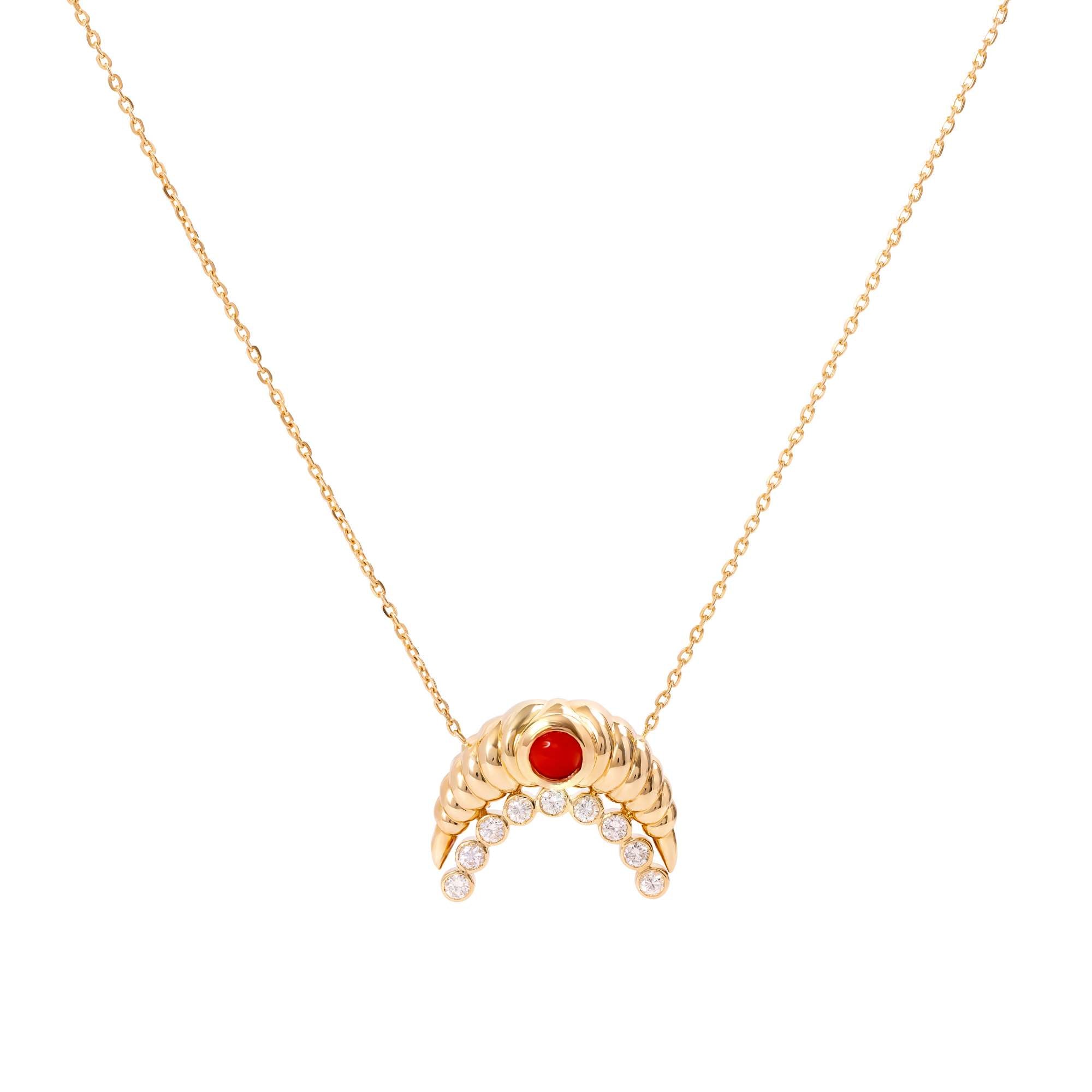 The Diamond and Coral Gold Moon Necklace by Nijma M Fine Jewelry features a crescent-shaped 18K yellow gold pendant with clear gemstones and a central red gemstone, displayed against a plain white background.