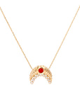 The Diamond and Coral Gold Moon Necklace by Nijma M Fine Jewelry features a crescent-shaped 18K yellow gold pendant with clear gemstones and a central red gemstone, displayed against a plain white background.