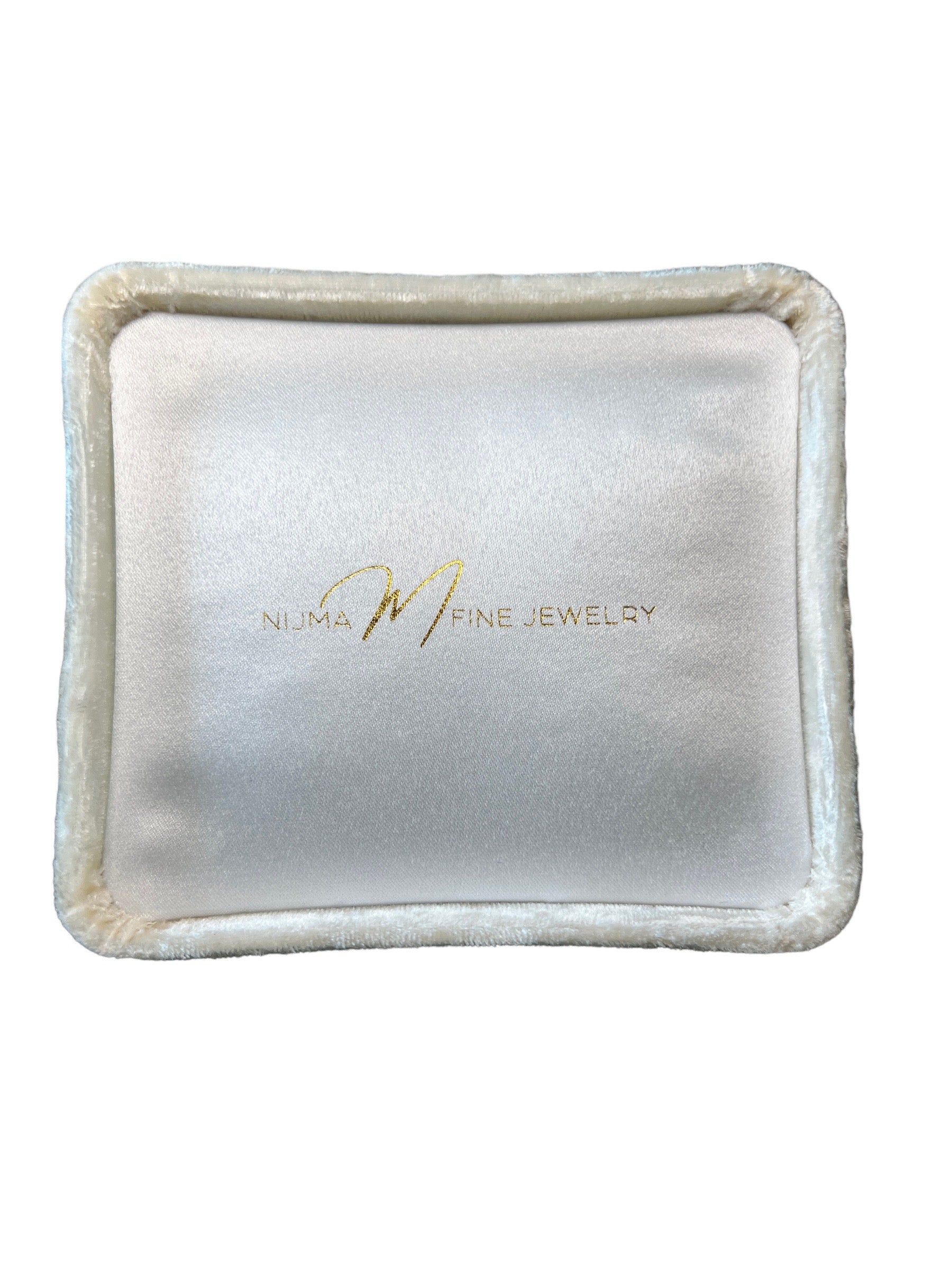 A close-up image of a white, square Jewelry Pochette Case with the text "Nijma M Fine Jewelry" in gold lettering on the surface. The case, resembling a white crushed velvet jewelry cushion, has a smooth, satin-like center and a soft, plush border.